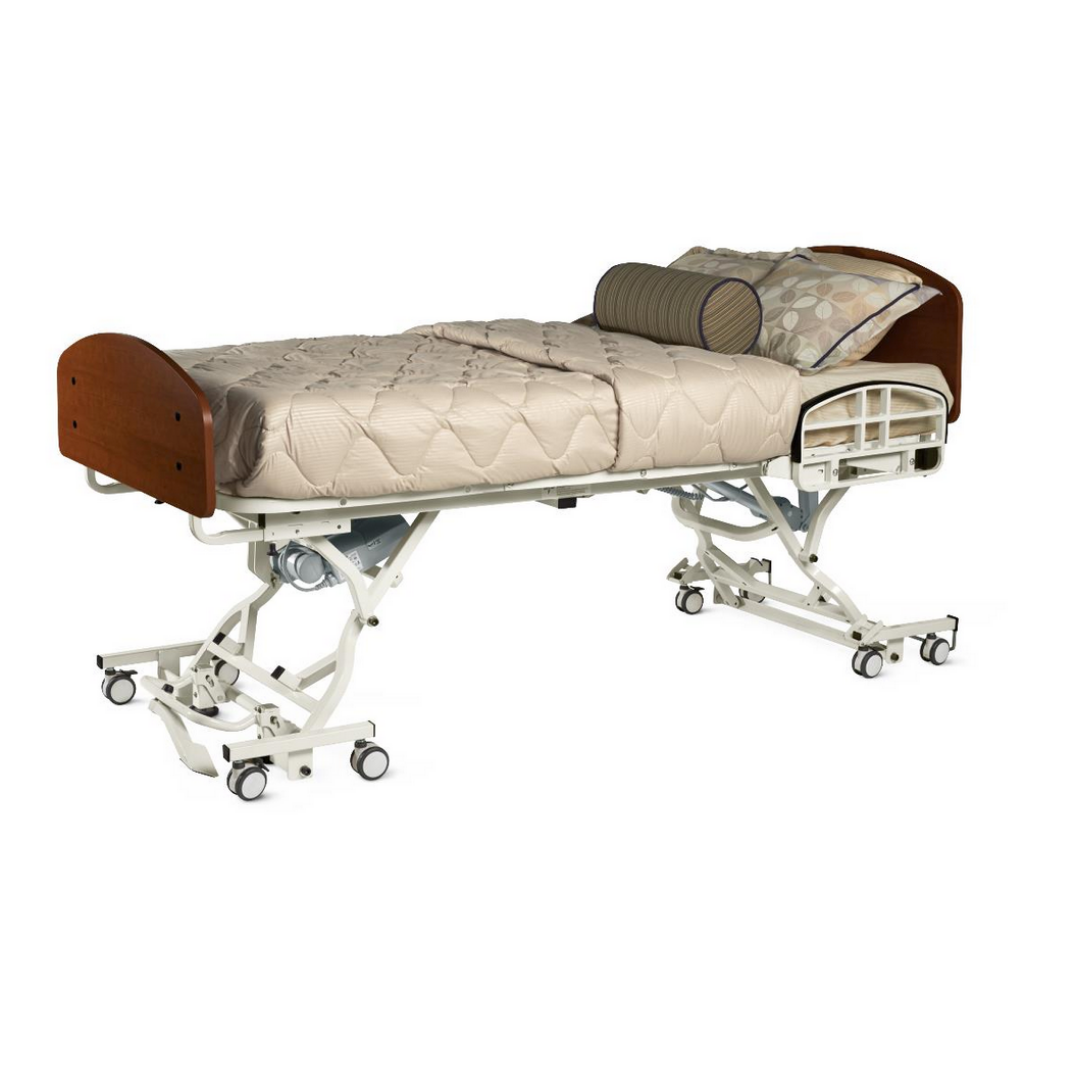 The Alterra 1385 Hi/Low Long-Term Care Hospital Bed features wheels, adjustable elevation, beige bedding, a patterned pillow, cylindrical cushion, and wooden head/footboards—designed for performance and safer patient handling.